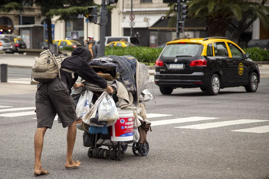 Hombre en situación de calle empujando un carrito con sus cosas